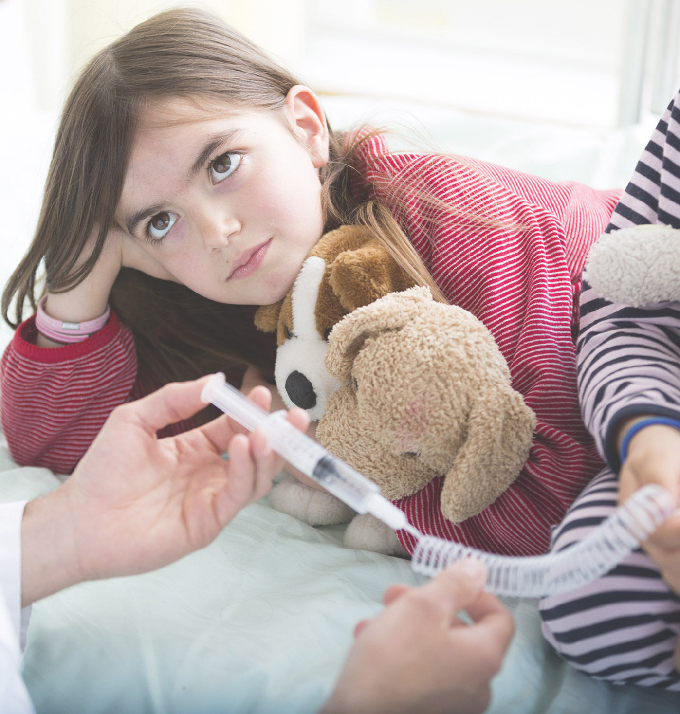 Child in hospital with teddy and syringe.